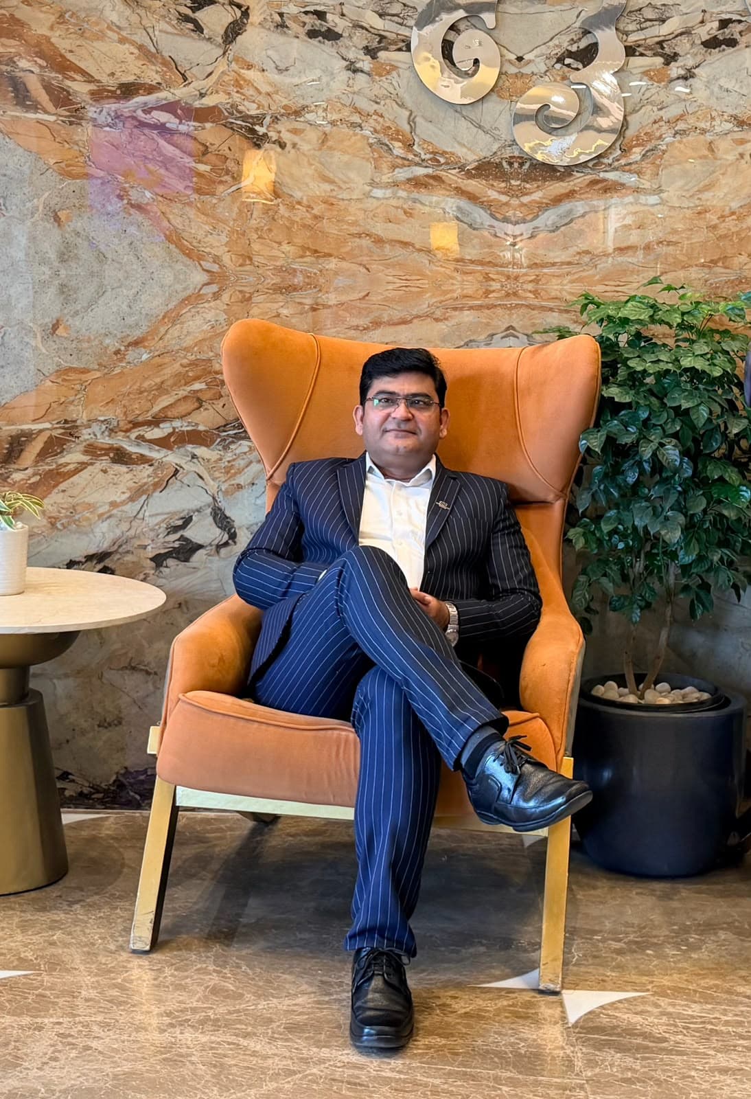 Aadesh Sharma seated in an armchair in a marble hotel lobby