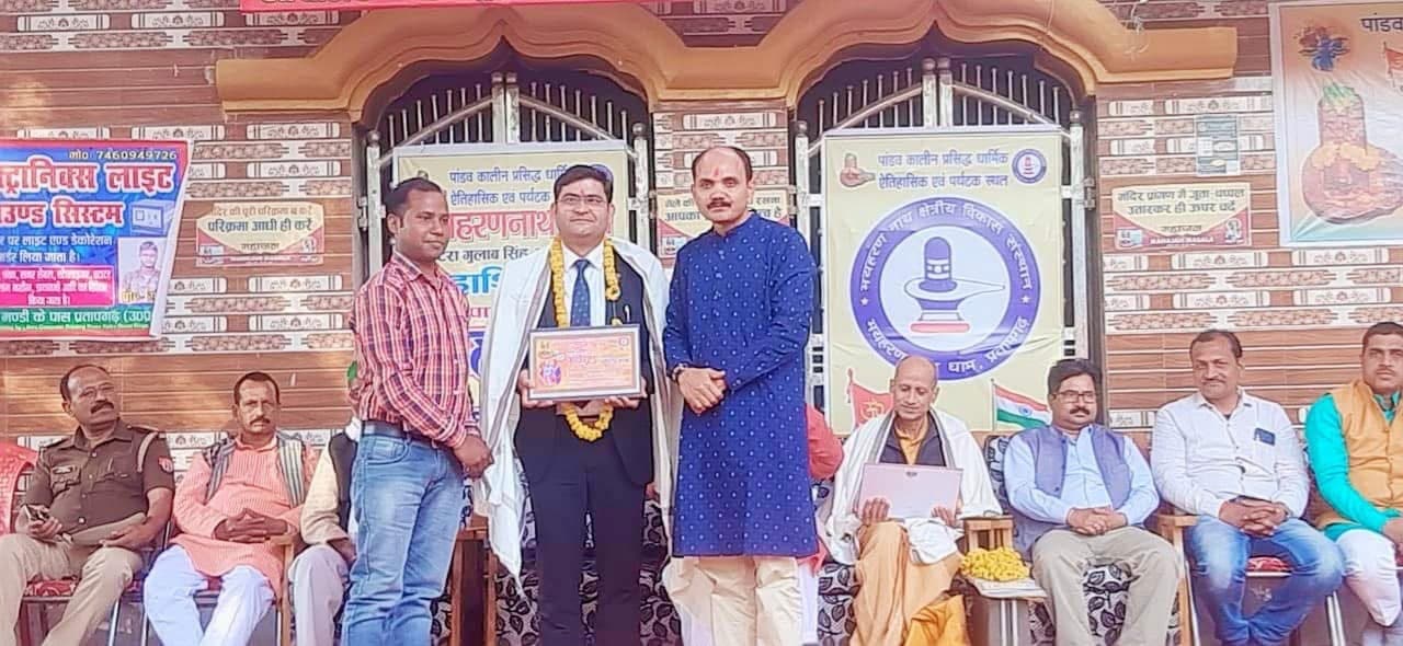 Aadesh Sharma holding a citation and wearing a garland after being honoured at a community event
