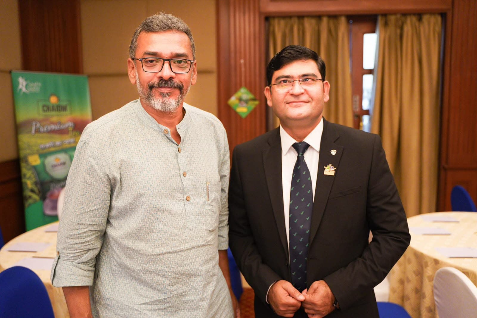 Aadesh Sharma standing with a guest at a business event