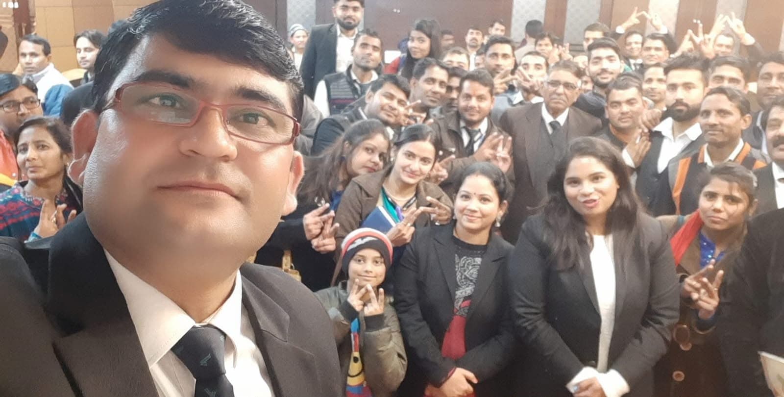 Aadesh Sharma taking a selfie with a large group of participants in formal wear